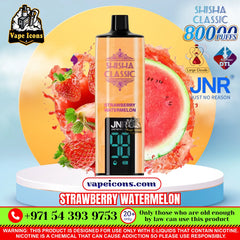 A vape product labeled 'Shisha Classic Strawberry Watermelon' centered on a promotional graphic with strawberries, watermelon slices, and fruit splashes. The package shows a peach-to-orange gradient body, a black mouthpiece, and a black front panel with blue digital display text.